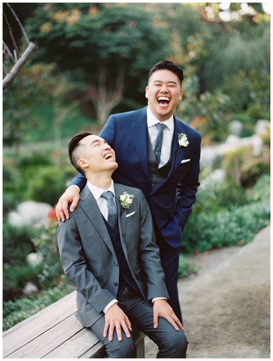 Two grooms laughing on their wedding day at the japanese friendship garden