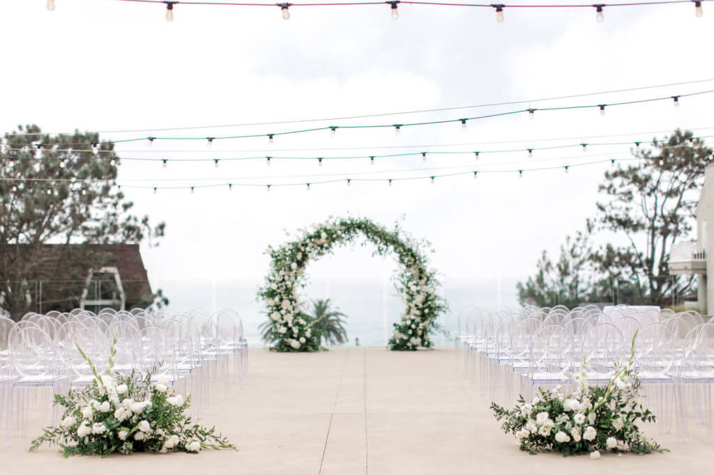 San Diego Wedding Photographer photography of round lush arch with white flowers and two end of aisle arrangements